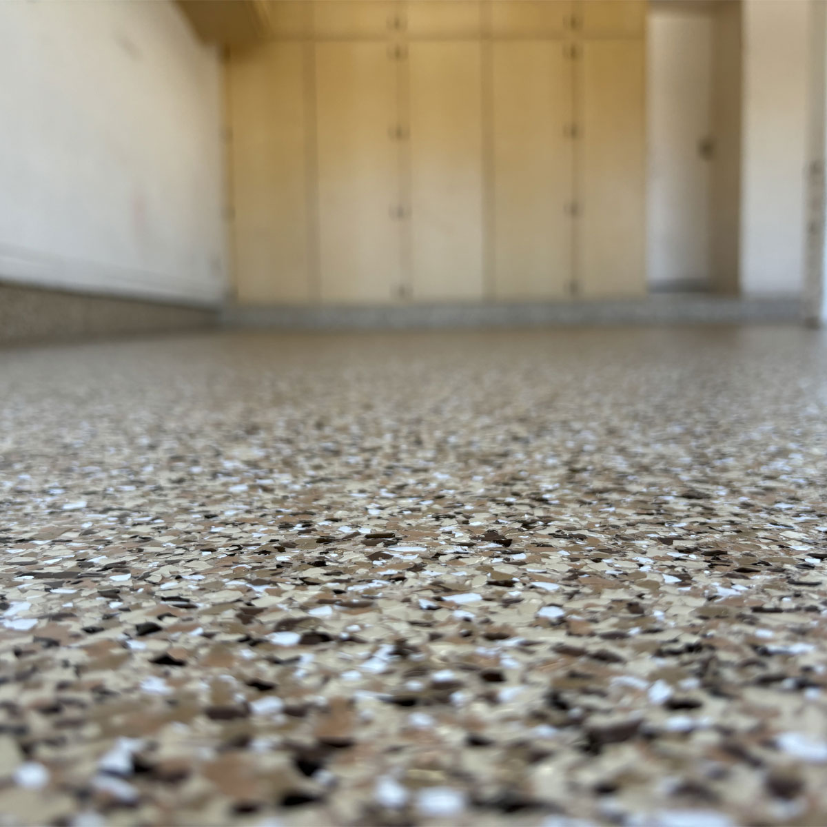 Epoxy garage floor with decorative flakes, showcasing a clean and durable surface, enhancing aesthetics for garage flooring solutions by Gear Up Garage.