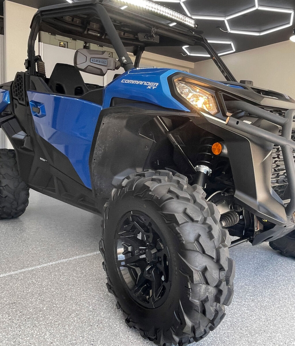 Blue off-road vehicle with large tires, showcasing the COMMANDER XT model, displayed in a modern garage setting.