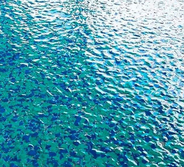 Water surface reflecting light, showcasing vibrant blue and green hues, emphasizing tranquility and clarity, relevant to garage transformation aesthetics.