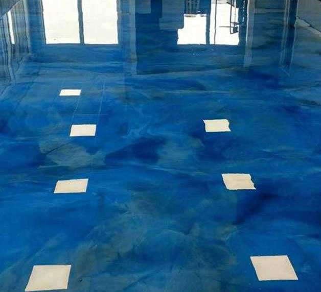 Epoxy flooring with a glossy blue finish and white accent tiles, showcasing a modern garage transformation by Gear Up Garage.