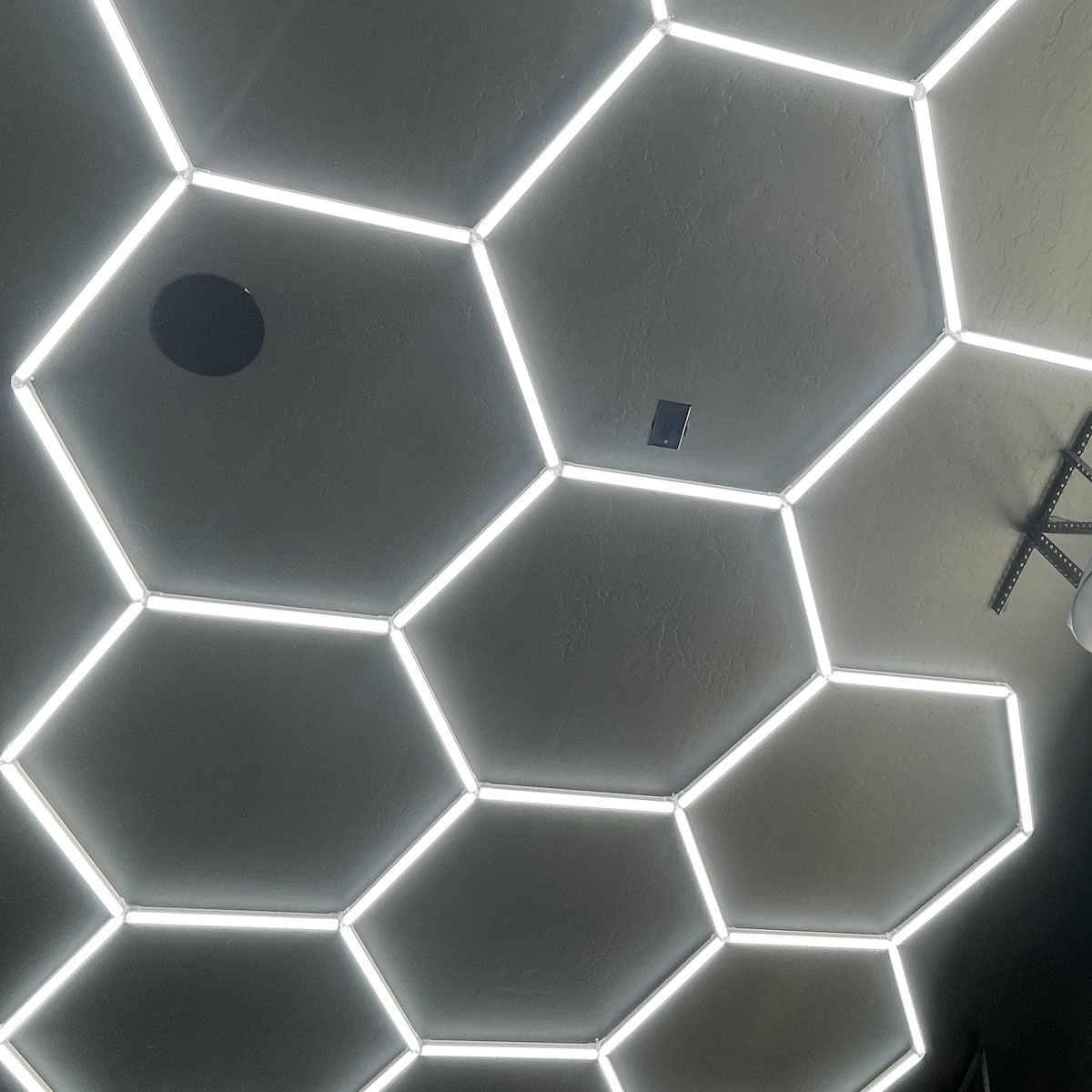 Hexagonal LED ceiling light design in a garage, showcasing modern lighting upgrades for enhanced visibility and aesthetics.