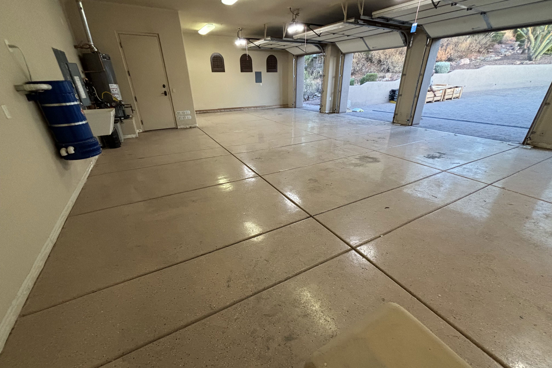 Clean and spacious garage interior with polished concrete floor, featuring a side door and garage door opening, suitable for garage door replacement and upgrades in Arizona.