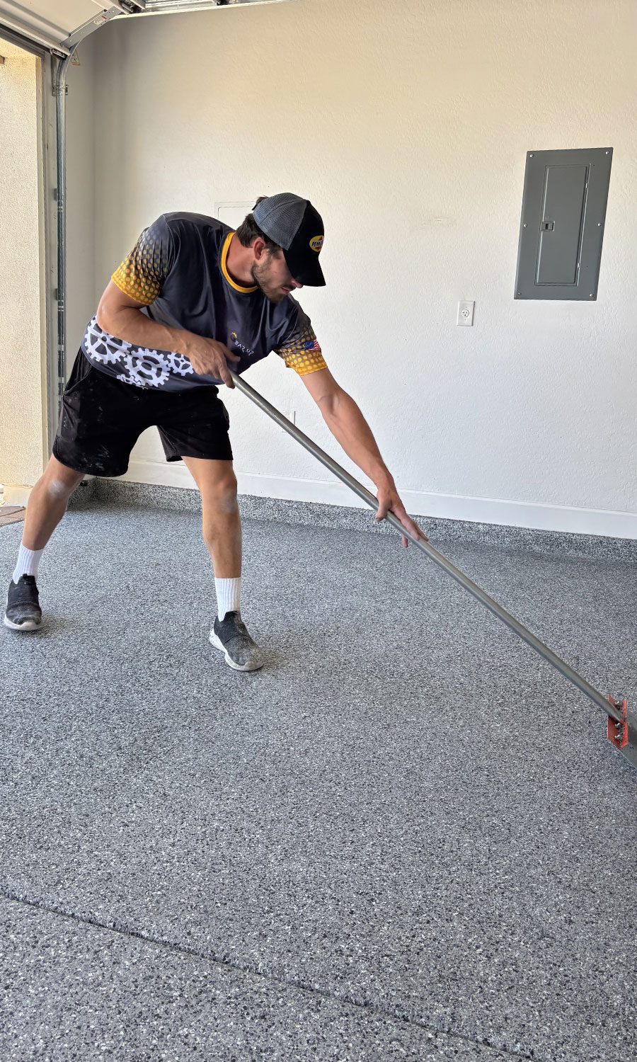 Man applying epoxy flooring in a garage, demonstrating precision craftsmanship for garage transformation services by Gear Up Garage.