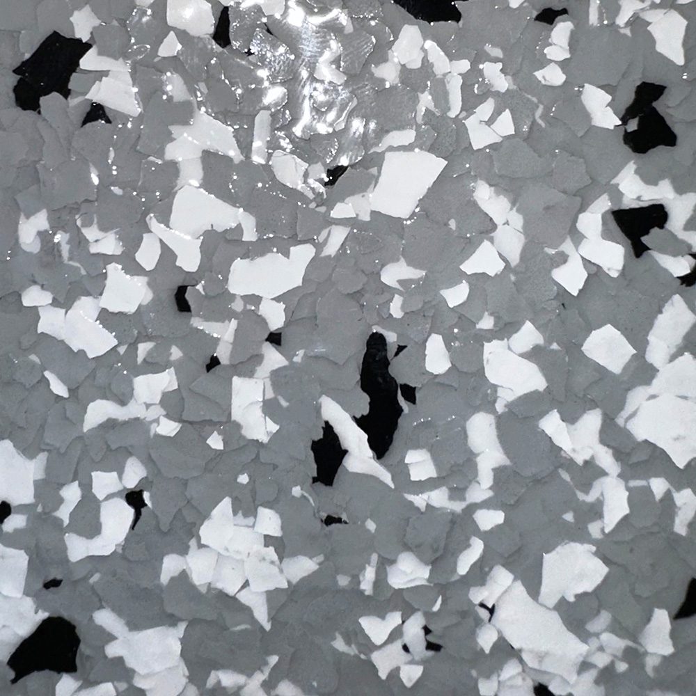 Light gray garage floor coating with scattered white and black flakes, showcasing a durable and stylish finish from the Standard Series color chart.